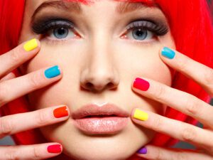 Closeup face of a beautiful  girl with  multicolor nails.