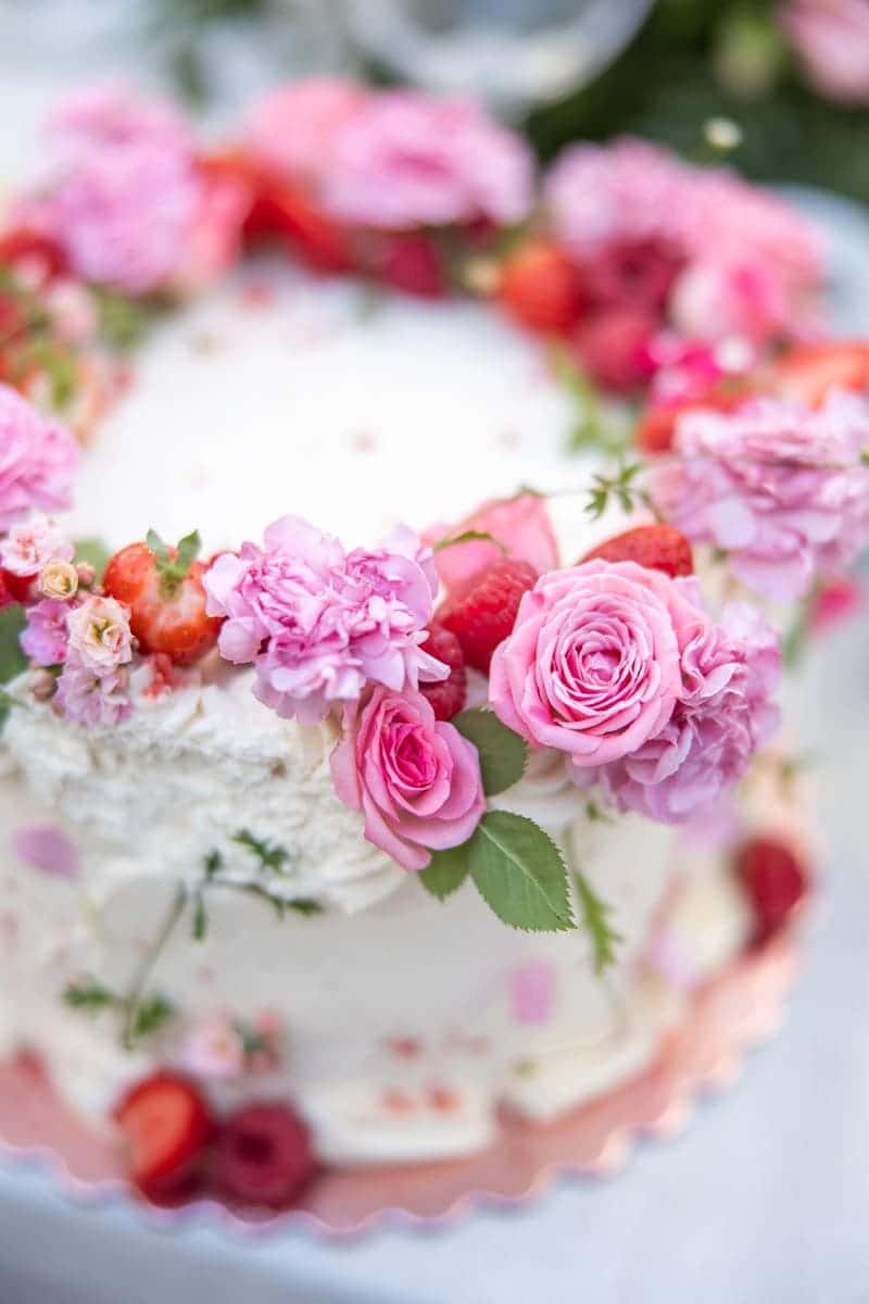 Tarta de boda decorada con rosas y flores en tonos rosados