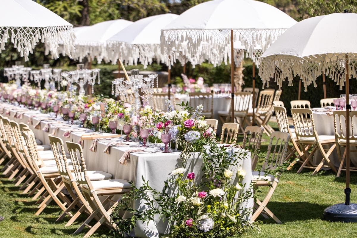 Mesa imperial con flores rosas y sombrillas blancas en una boda diseñada por Madison Park